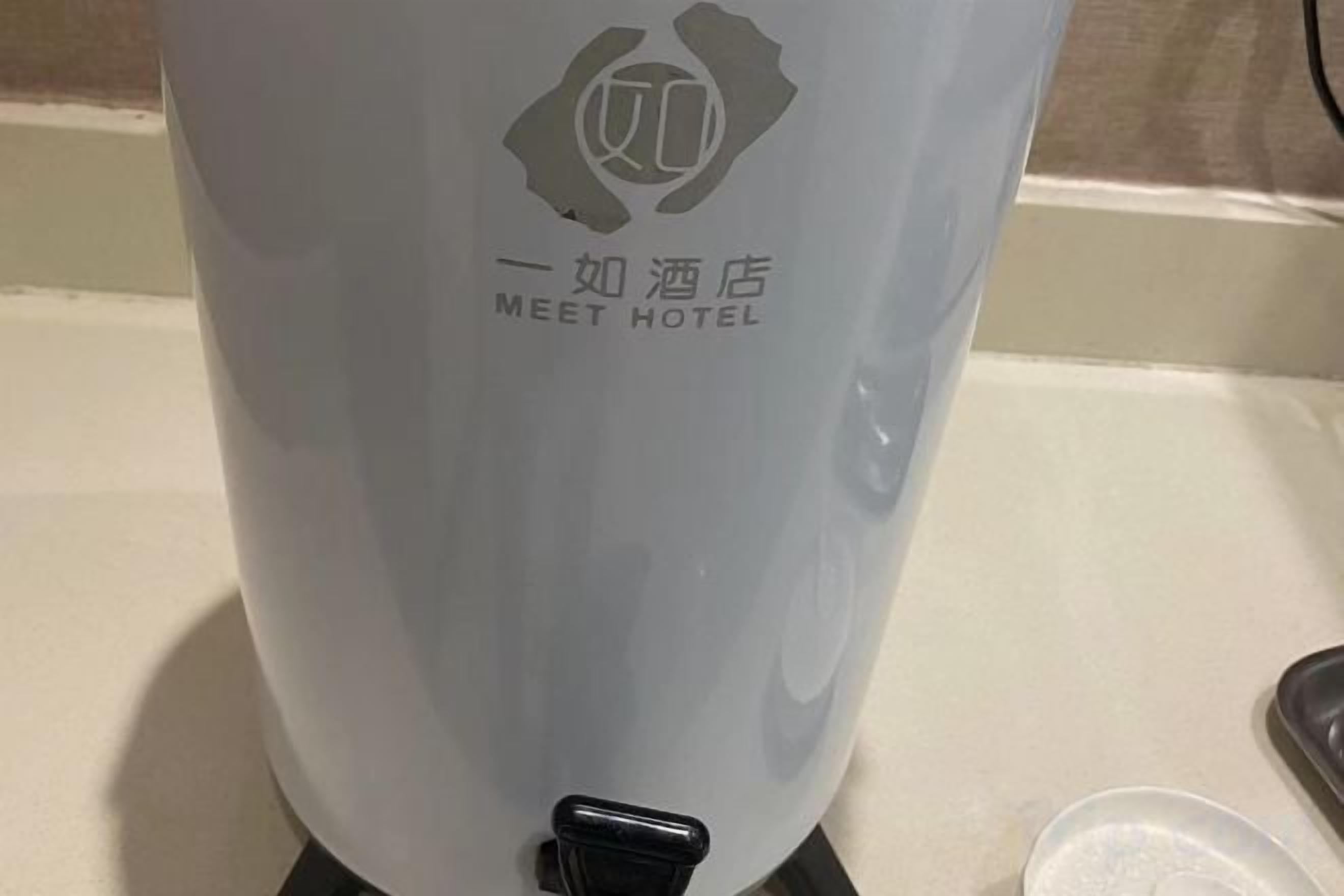 A water dispenser with a logo and text indicating it's from a hotel named 'MEET HOTEL'.