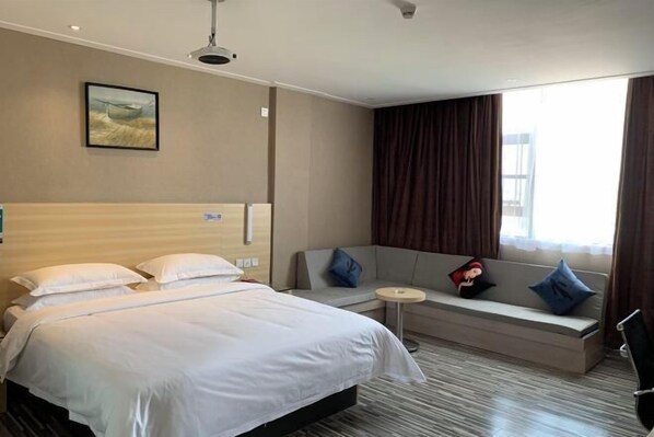 A hotel room with a bed, a sofa, a small round table, and a window with curtains. - Yiru Hotel (Xinfeng) (Xinfeng)