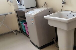 Un área de lavandería con lavadora, lavabo y cesto.
