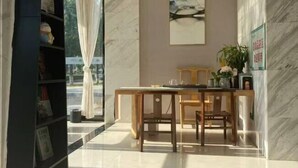 A hotel lobby with a marble floor, a wooden reception desk, and a bookshelf. - Yiru Hotel (Xinfeng) (Xinfeng)