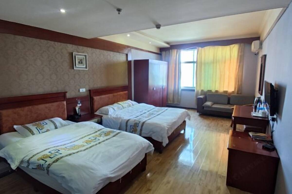 Une chambre d’hôtel avec deux lits, un canapé, une télévision et un bureau.