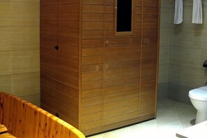 A wooden sauna with a small window, a toilet, and a wooden bench.