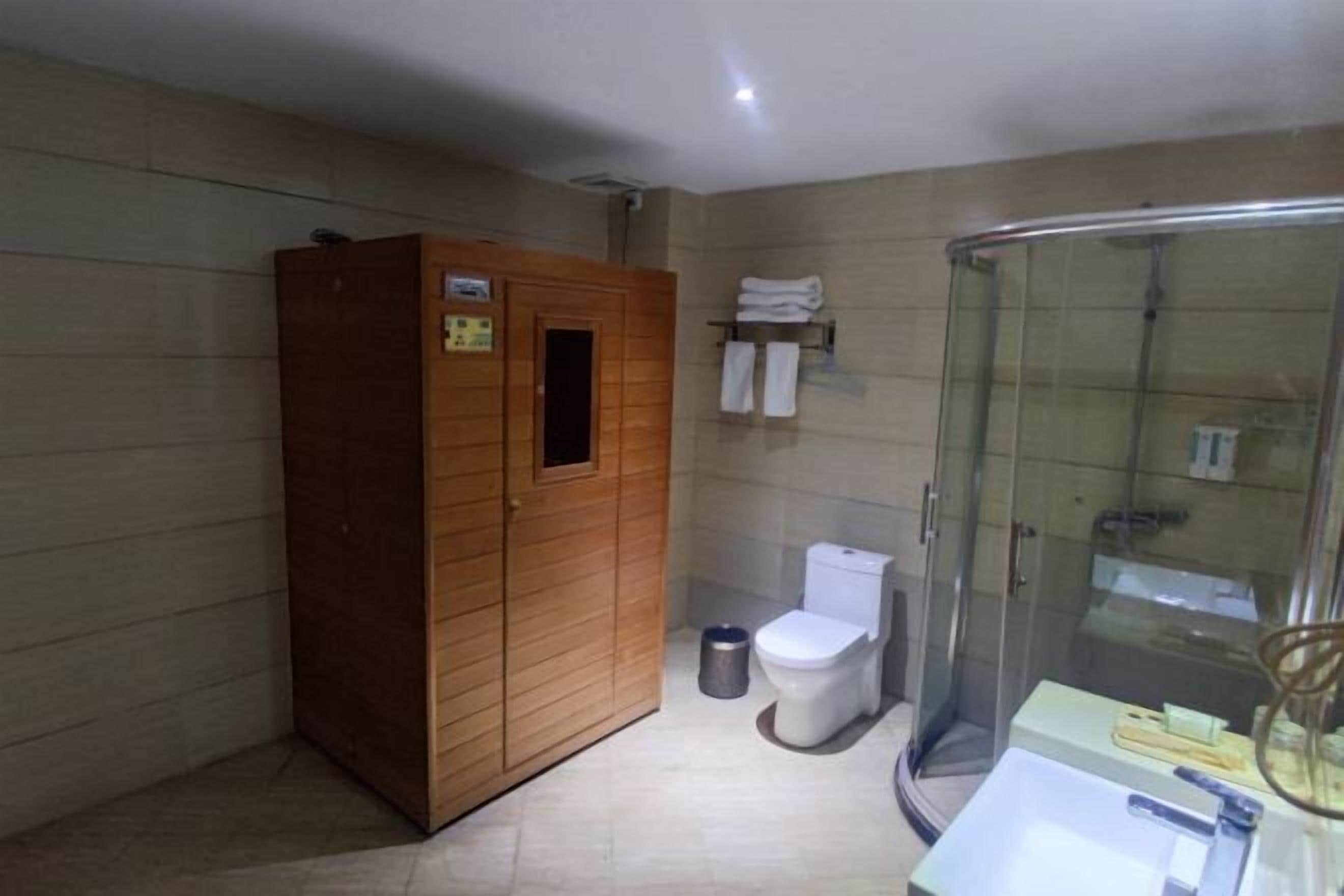 Une salle de bain avec un meuble en bois, des toilettes, une douche en verre et un lavabo avec des articles de toilette.