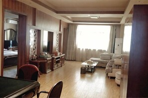 A hotel room with a pool table, a sofa, a coffee table, and a TV.