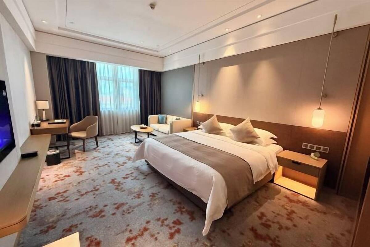 Une chambre d’hôtel moderne équipée d’un grand lit, d’un bureau, d’une chaise, d’une télévision et d’un canapé.