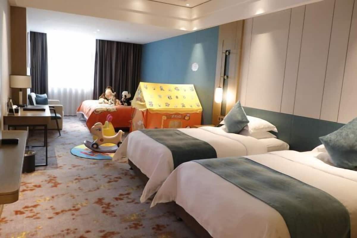 Une chambre d’hôtel avec deux lits, un bureau, une chaise, une lampe et une maison de jeu.
