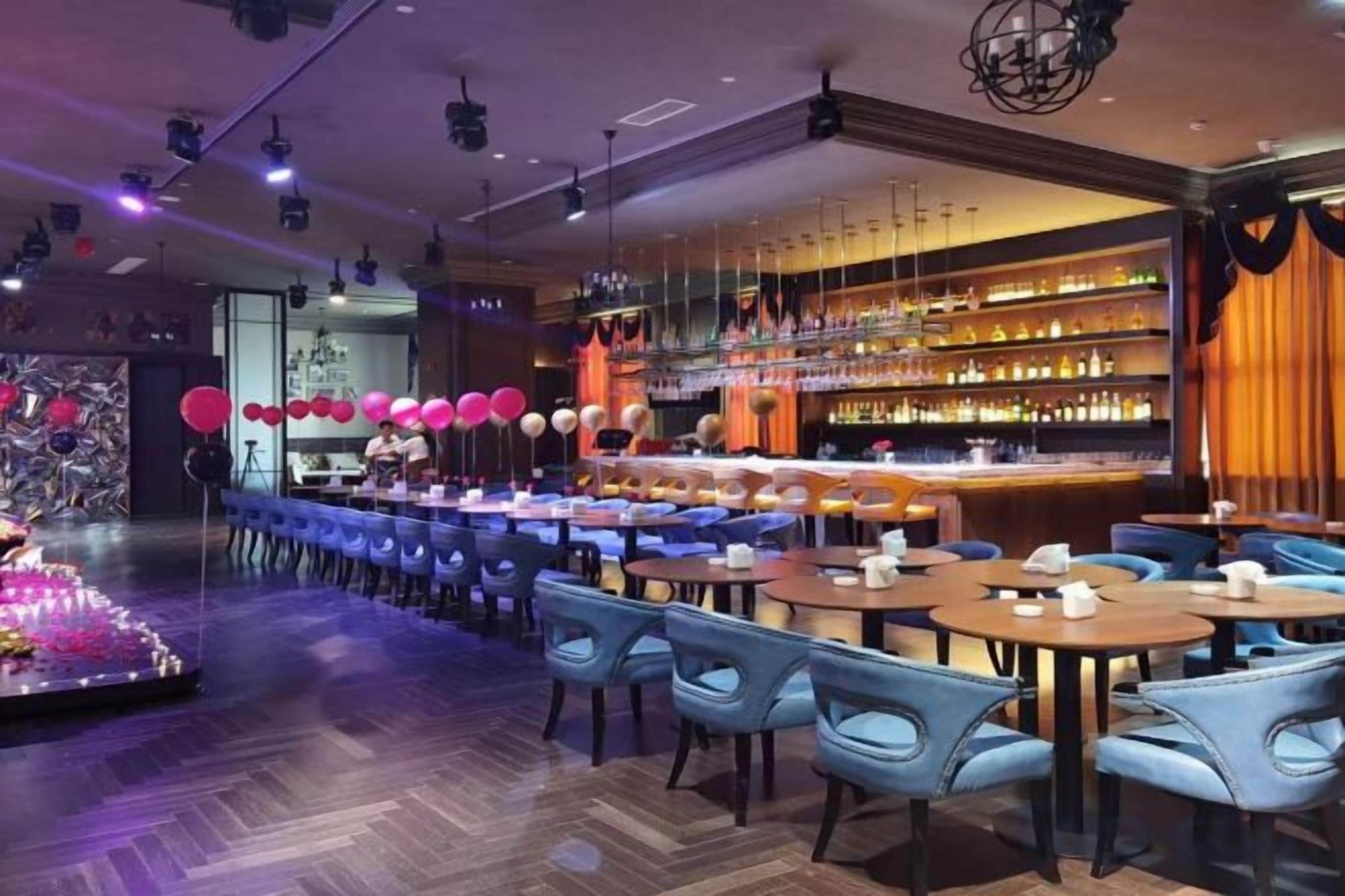 Un'area bar con diverse sistemazioni per sedersi, un bancone e una varietà di bottiglie sugli scaffali.