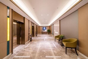 A hotel corridor with a marble floor, elevators, a reception desk, and a green chair. - Fuqing Yonghong Hotspring Resort (Fuqing)