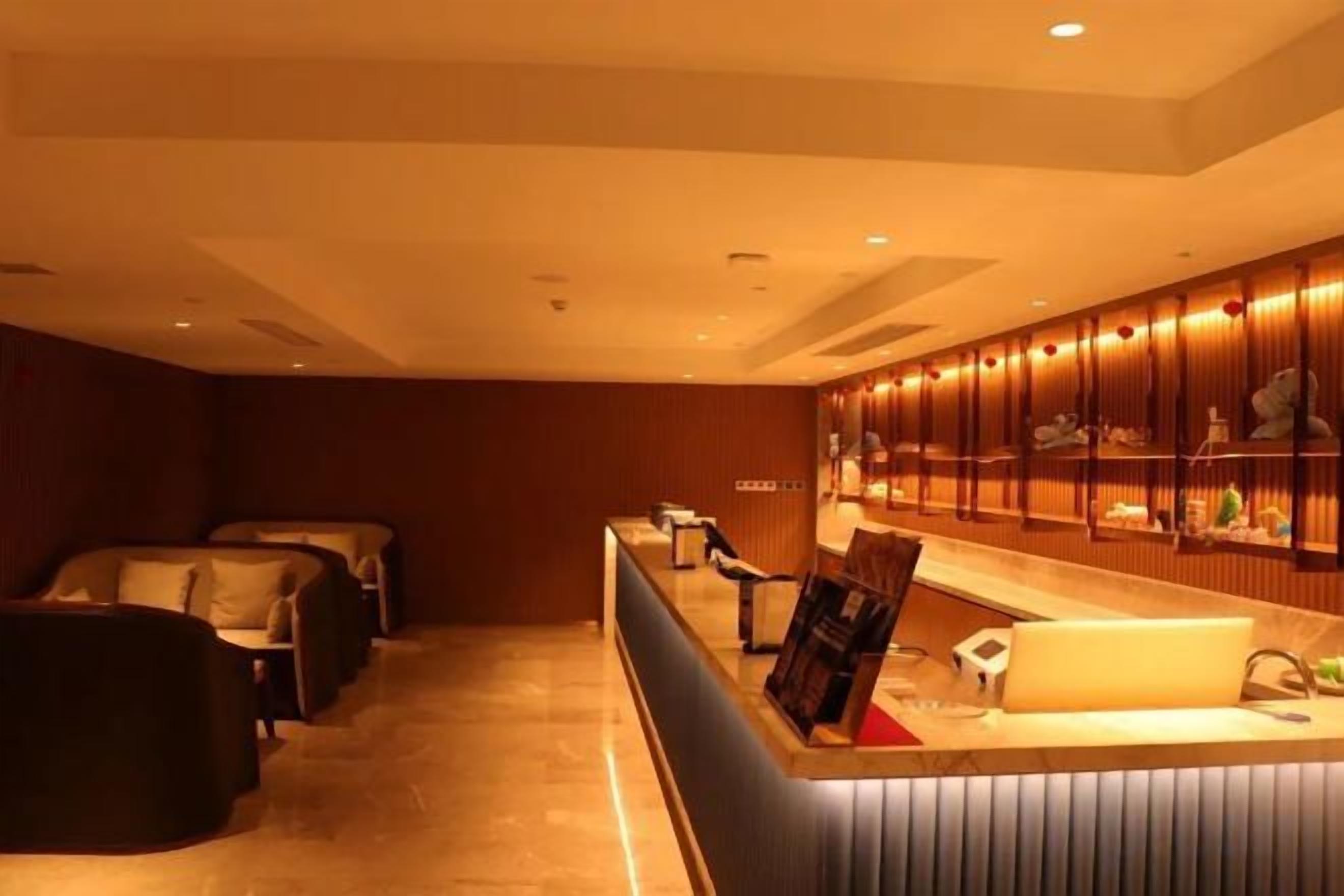 A hotel lobby with a reception desk, seating area, and a wall of framed pictures.
