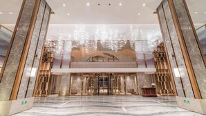 Um hall amplo com piso de mármore, balcão de recepção e design arquitetônico moderno.
