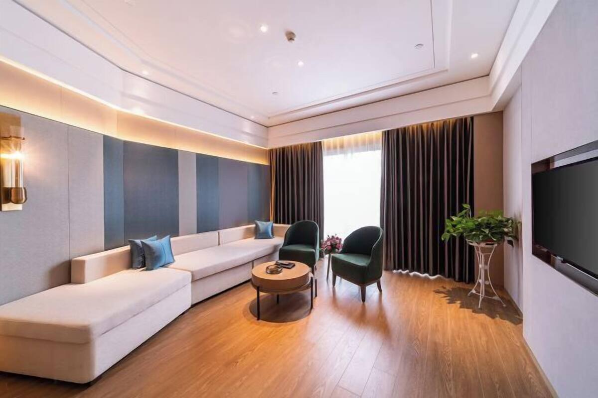 Un salon moderne comprenant un canapé, deux fauteuils, une table basse et un téléviseur.