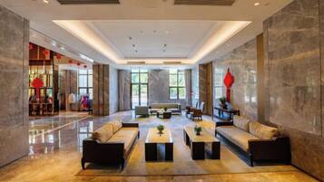 A spacious lobby with a seating area, a reception desk, and a view of the outdoors.