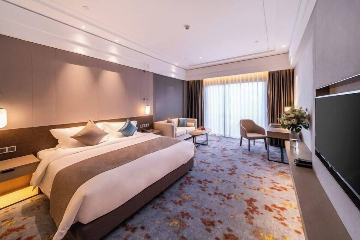 Une chambre d’hôtel avec un grand lit, un bureau, une chaise et un téléviseur.