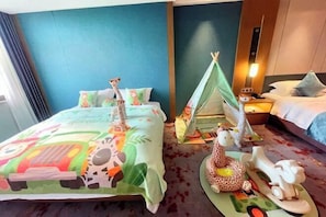 A hotel room with a bed featuring a colorful animal-themed bedspread, a small tent, and a giraffe-shaped pillow. - Fuqing Yonghong Hotspring Resort (Fuqing)