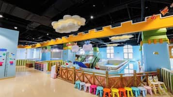 A children's play area with a climbing wall, colorful stools, and a play structure.