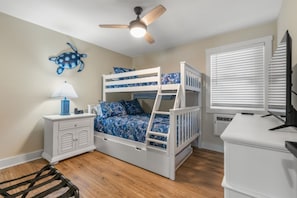 A child's bunk bed with a ceiling fan, a nightstand with a lamp, and a window with blinds. - 2BR Condo at Ocean Pier IV 238 (North Myrtle Beach)