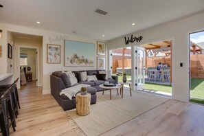 Een moderne woonkamer met een grijze bank, een bijzettafeltje en een bordje met de tekst 'Welcome'.