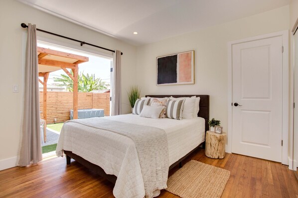 Une chambre avec un grand lit, une structure de plafond en bois, une porte blanche et une vue sur l’extérieur.