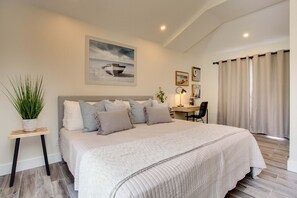 Cozy retreat with a large bed, side table, and desk, perfect for relaxation and work.