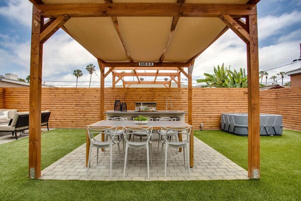 Enjoy casual dining under a covered pergola with a long table and six chairs.