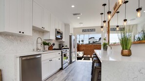 A modern kitchen with white cabinets, stainless steel appliances, and a herringbone tile backsplash.