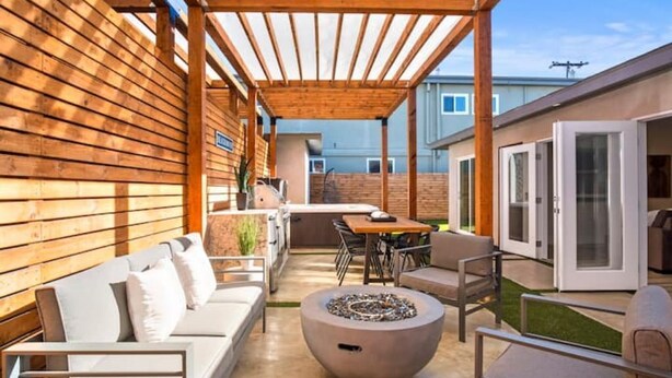 A covered patio area with a wooden pergola, outdoor seating, a fire pit, and a view of the backyard. - Dream HOUSE❤️ Walk to Beach & Bay - Hot Tub + AC + FirePit + Bikes (San Diego)