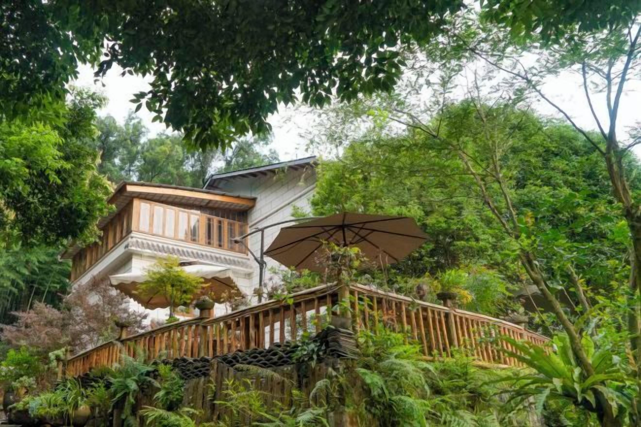 A traditional wooden building with a balcony, surrounded by lush greenery.