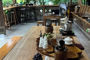 A wooden dining table with a rustic centerpiece, a fan, and a coffee maker.