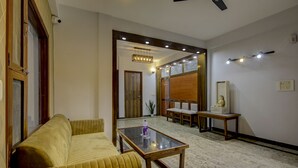A modern living room with a sofa, a glass-top coffee table, and a wooden bench. - Treebo Sai Village, Manesar (Gurugram)
