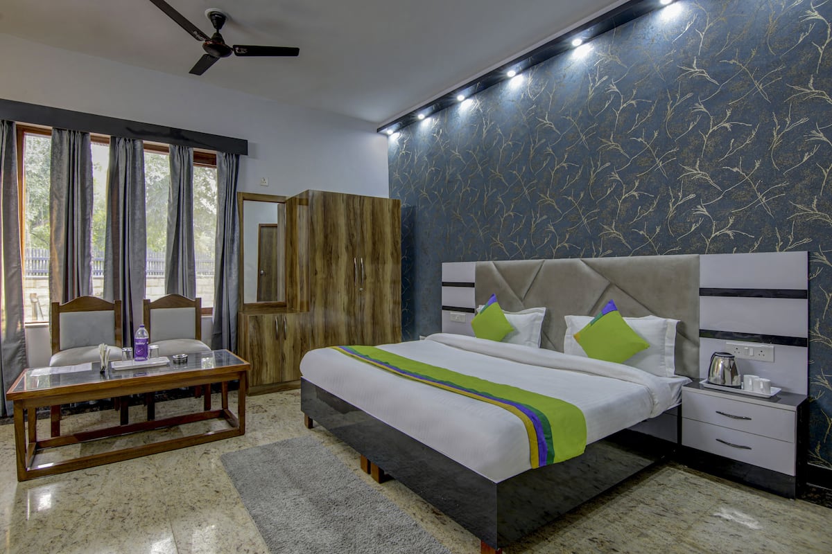 A hotel room with a bed, bedside table, and a desk with chairs.