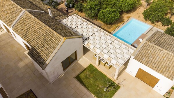 Zona de piscina en la azotea con techo de baldosas, piscina y follaje circundante.