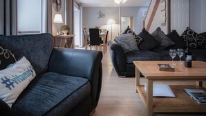 A modern living room with a sofa, a coffee table, and a dining area.