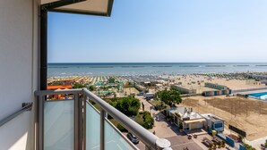 A balcony with a view of a beach, a pool, and a parking area. - Little Hotel (Cesenatico)