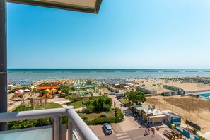 A beachside view with a parking area, beach umbrellas, and a small building. - Little Hotel (Cesenatico)