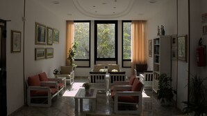 A spacious living room with a large window, a white sofa set, a coffee table, and a bookshelf. - Little Hotel (Cesenatico)