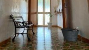 A hallway with a patterned floor, a bench, and a door leading to another room.