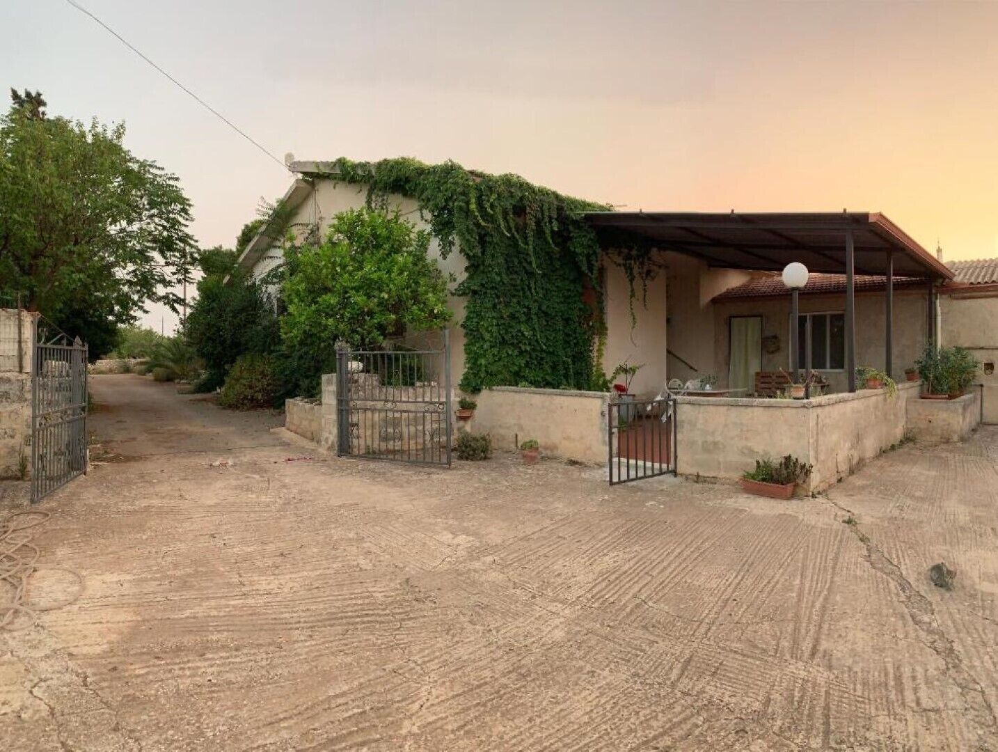 A residential property with a gated entrance, a covered porch, and a garden area.