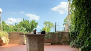 An outdoor patio with a stone table and a wooden bench.