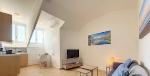A compact living space with a kitchenette, dining area, and a TV on a wooden stand. - N&J - CITY BREAK - Central - Very close sea (Niza)