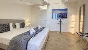 A modern hotel room with a large bed, a bedside table with a lamp, a wall-mounted TV, and a mirror.