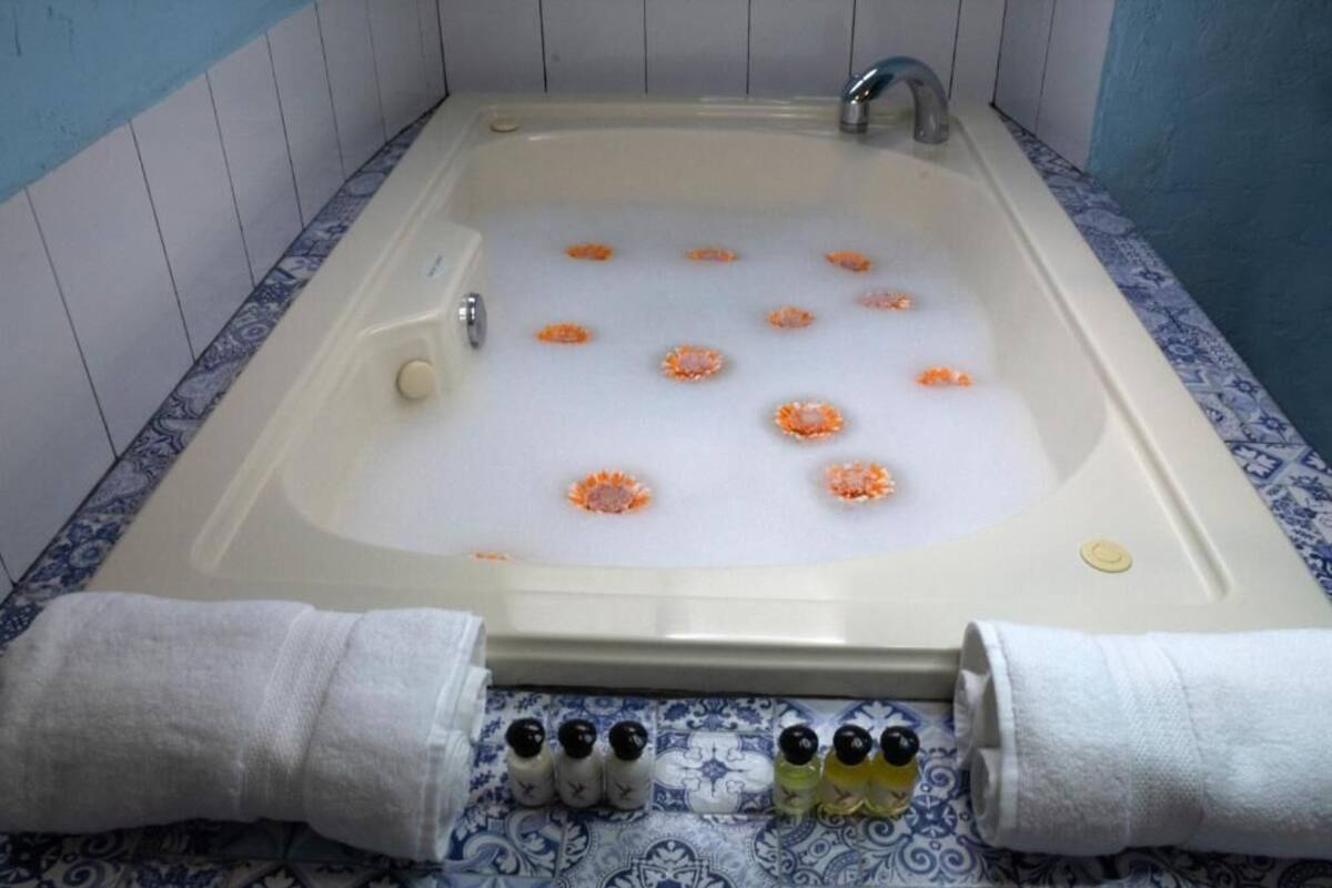 Deluxe kamer | Badkamer | Een bubbelbad, een hydromassagedouche, handdoeken
