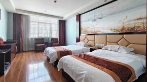 Een hotelkamer met twee bedden, een bureau, een stoel en een groot schilderij aan de muur.