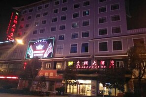 Un hôtel à plusieurs étages, doté d’une enseigne lumineuse et d’une grande enseigne au néon bien visible au rez-de-chaussée.