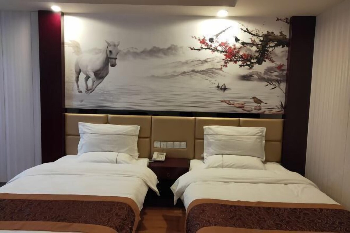 Ein Hotelzimmer mit zwei Betten, einem Bettkopfteil mit einem Gemälde und einem Nachttisch mit einem Telefon.