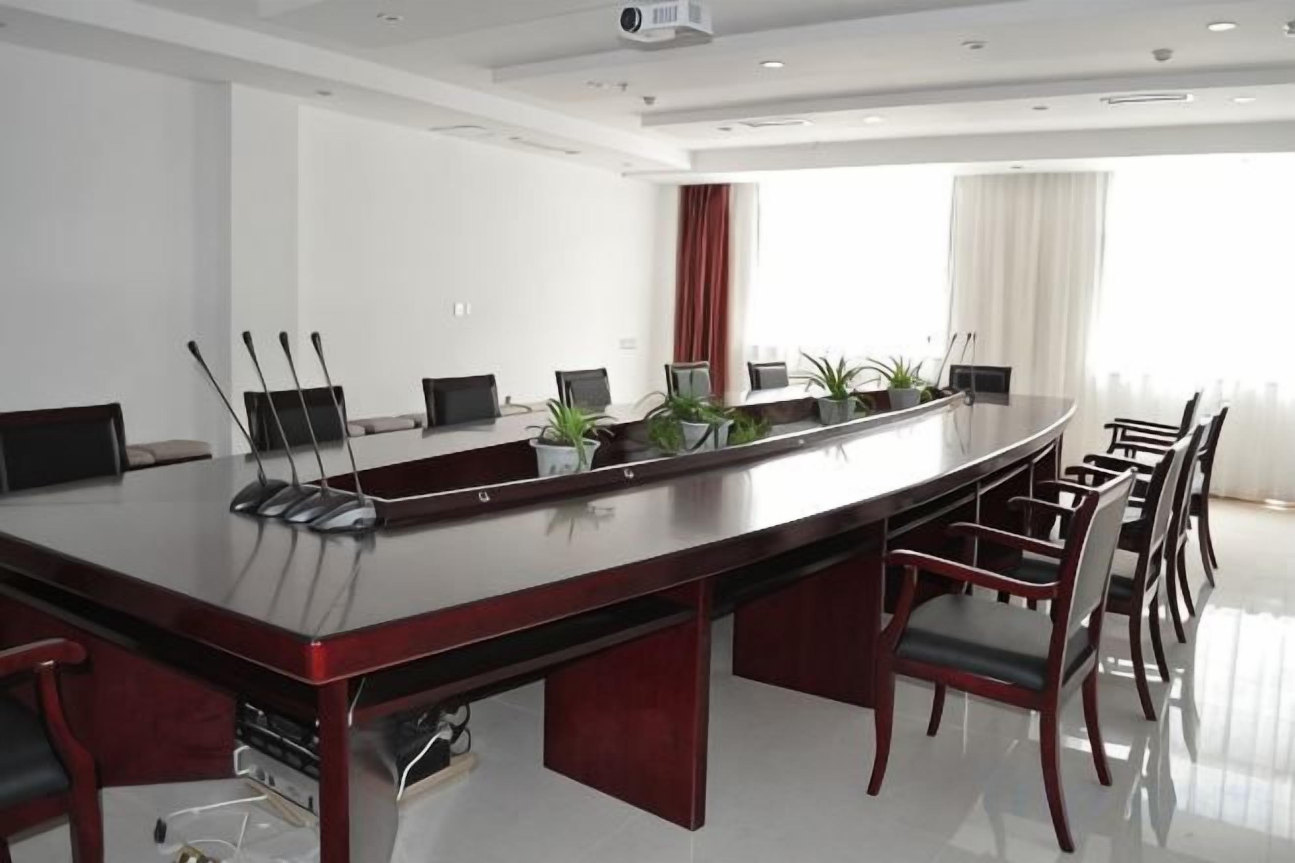 Uma sala de conferência com uma mesa comprida, cadeiras e um projetor.
