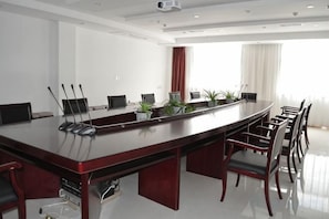 Een vergaderruimte met een lange tafel, stoelen en een beamer.