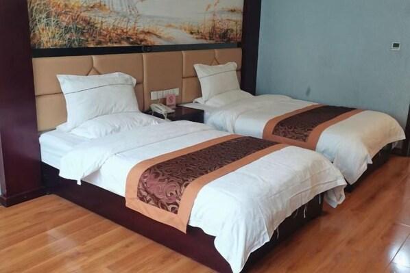 Habitación de hotel con dos camas, piso de madera y un cuadro grande en la pared.