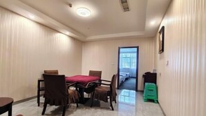 Een hotelkamer met een eettafel, stoelen, een bed, een klein krukje en een nachtkastje.