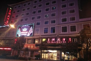 Um hotel com vários andares, com letreiros iluminados, um neon chamativo e uma fachada com caracteres chineses.