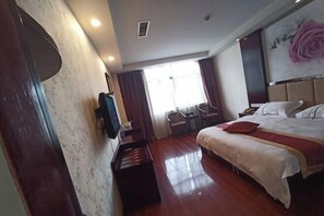 Ein Hotelzimmer mit Bett, Fernseher, Schreibtisch und Stuhl.